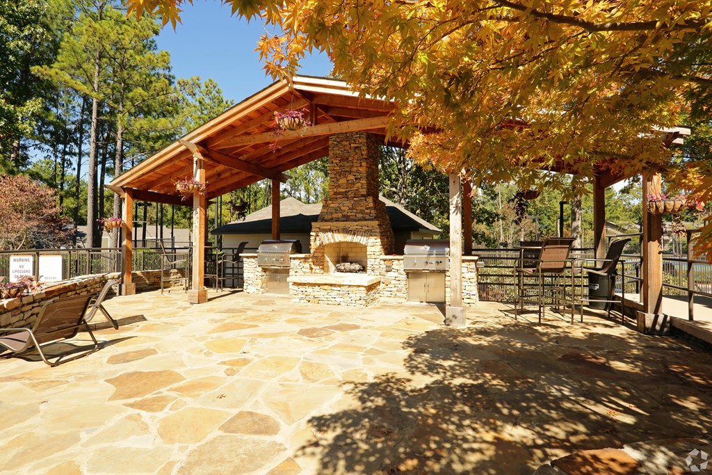 A patio with a fireplace and a table surrounded by trees.